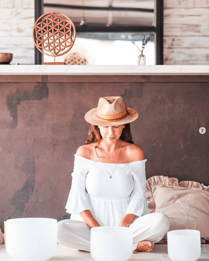 Tanya seated quietly in white linen with crystal singing bowls in her Ibiza studio